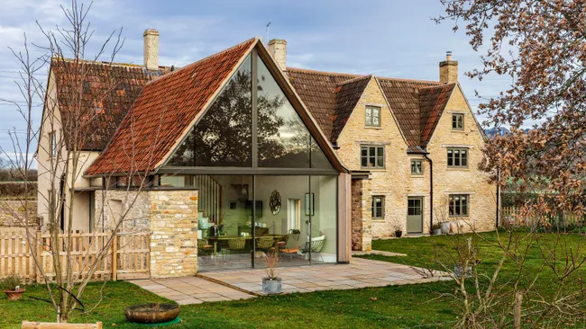 A large extension with glass curtain wall showing a dining room within