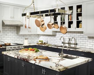 A black kitchen idea with black lower cabinets and island, and white upper cabinets and subway tiling
