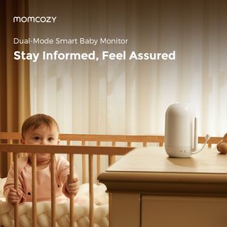 An infant sits up in its crib holding the railing looking toward the camera for a Dual-mode Smart Baby Monitor.