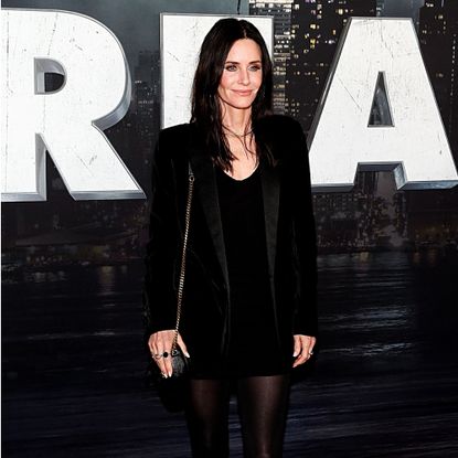 Courteney Cox on red carpet with scream poster in background