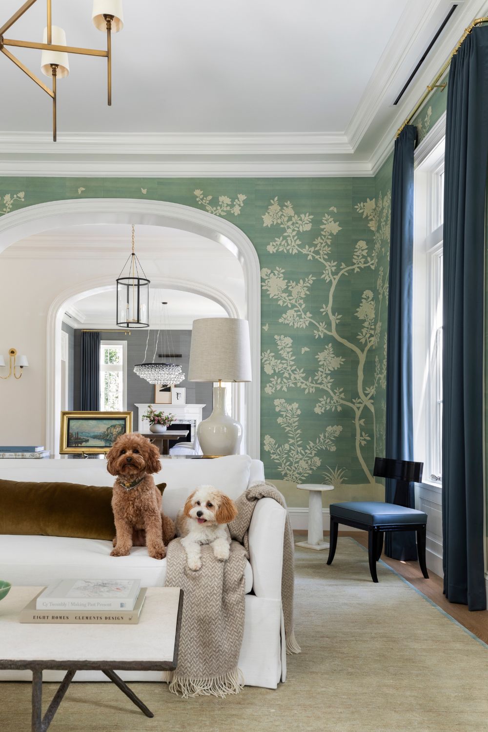 a green floral mural wallpapered living room with a white linen couch with two dogs sat on it