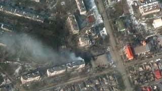 Apartment blocks burn in a bombed residential district.