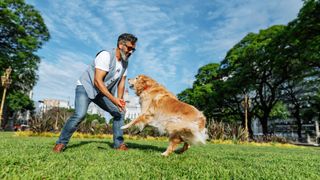 man playing in park with dog