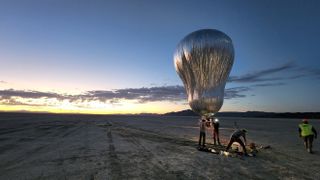 people adjusting large silver balloon against desert landscape