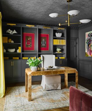 gray home office with gray walls, shelving and ceiling, yellow accents, rug, desk and chair, artwork, retro pendant light