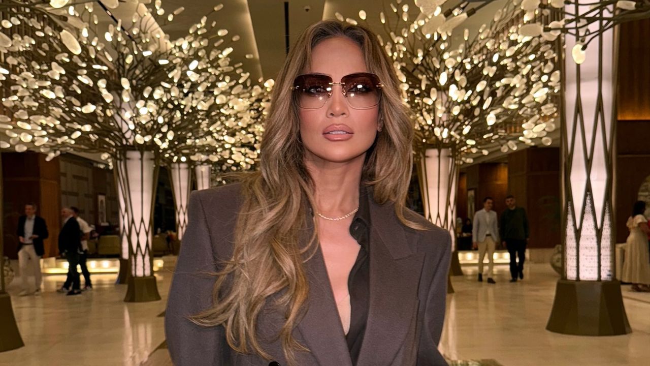 Jennifer Lopez wearing a brown suit in front of lights in a mall