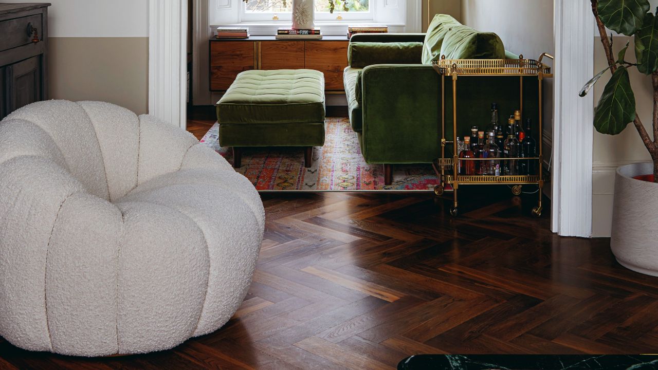 White boucle armchair, green velvet sofa and ottoman, gold bar cart