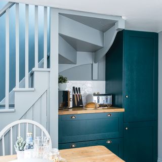 blue kitchen with staircase and wooden dining table