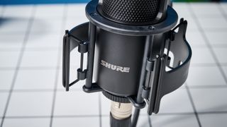 the Shure sm4 condenser musician microphone photographed against a blue background with a physical magnetic pop filter