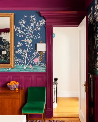 A dining room painted raspberry pink with a green chair