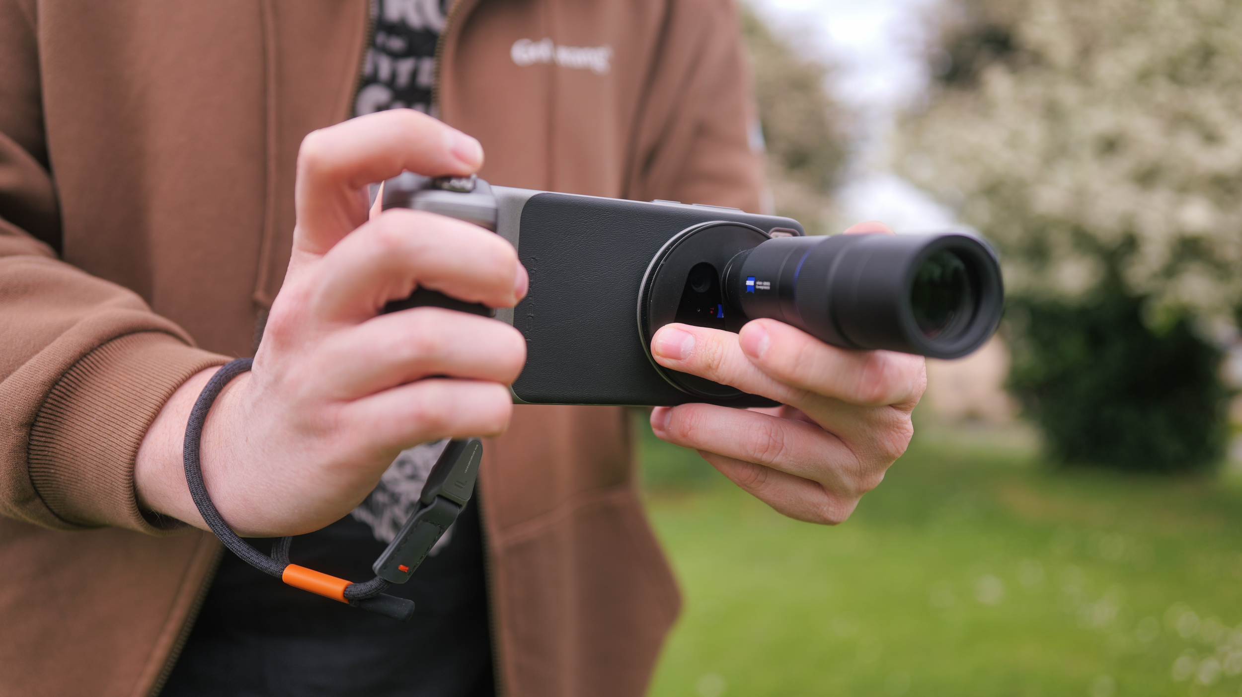 Vivo X200 Ultra phone with a telephoto lens attached held in a pair of hands outside