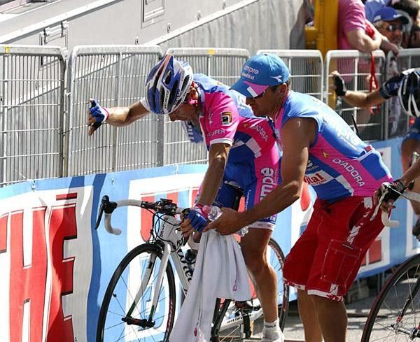 An exhausted Cunego holds onto the barriers after the finish line