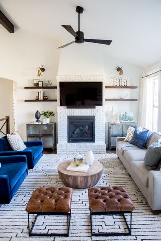 living room with blue sofa, patterned rug, leather footstools, shelving each side of tv