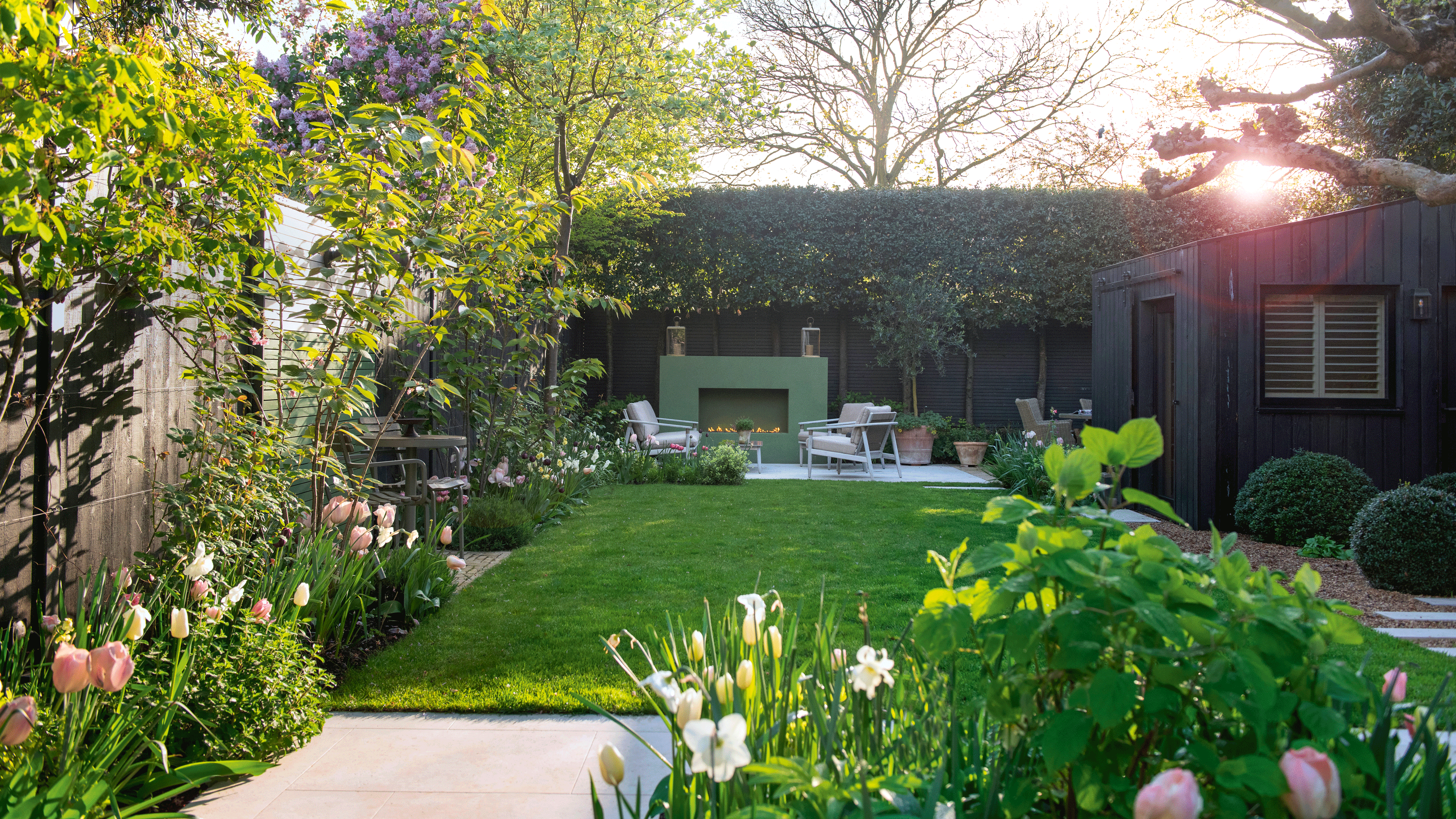 a garden with a patio area and large green outdoor fireplace and seating in front