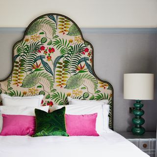 Oversize headboard with botanical fabric and bed with pink cushions