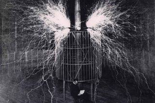Nikola Tesla, in his Colorado Springs laboratory in 1899, sits in front of the operating transformer.