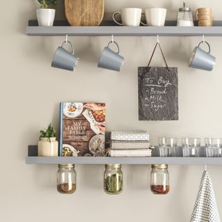 kitchen shelves with mugs on hooks and cookery book with under shelf storage