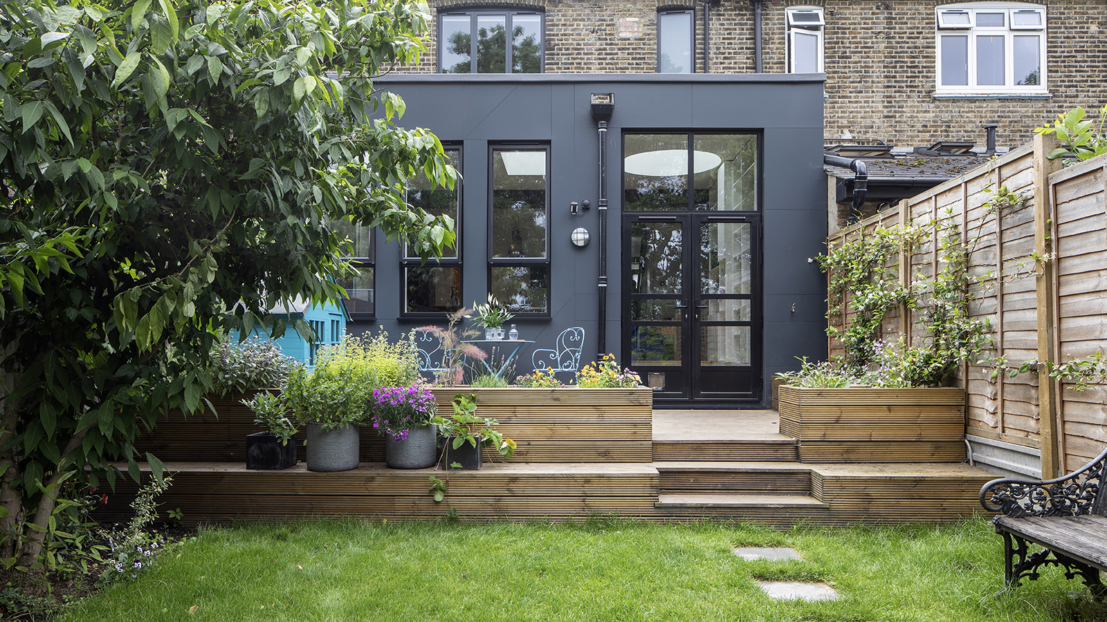 A modern extension with a raised deck in front and raised garden beds