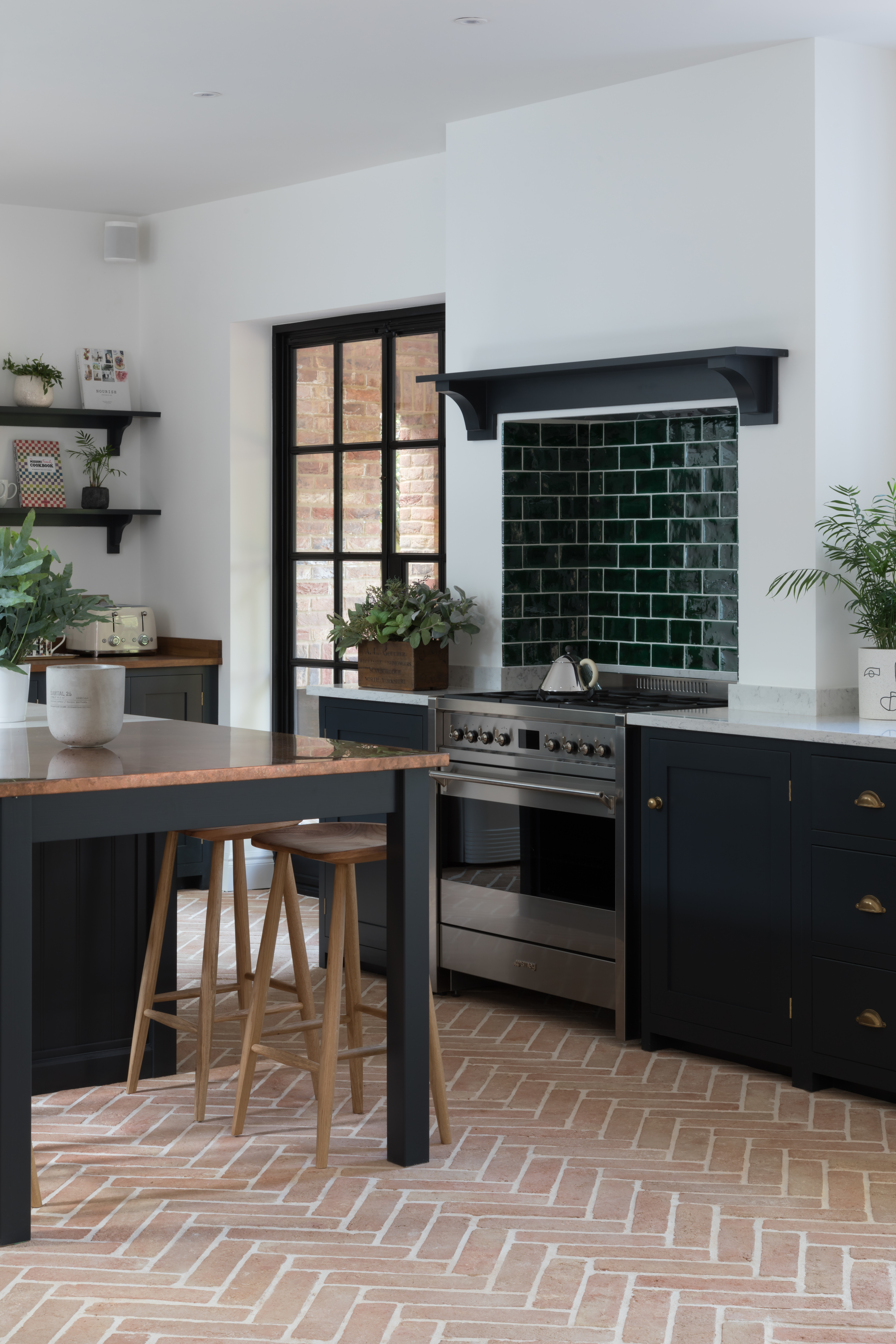 A herringbone terracotta tile floor in a black and white kitchen.