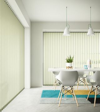 White Vertical blinds in a dining room with blue rug and white kitchen table and chairs