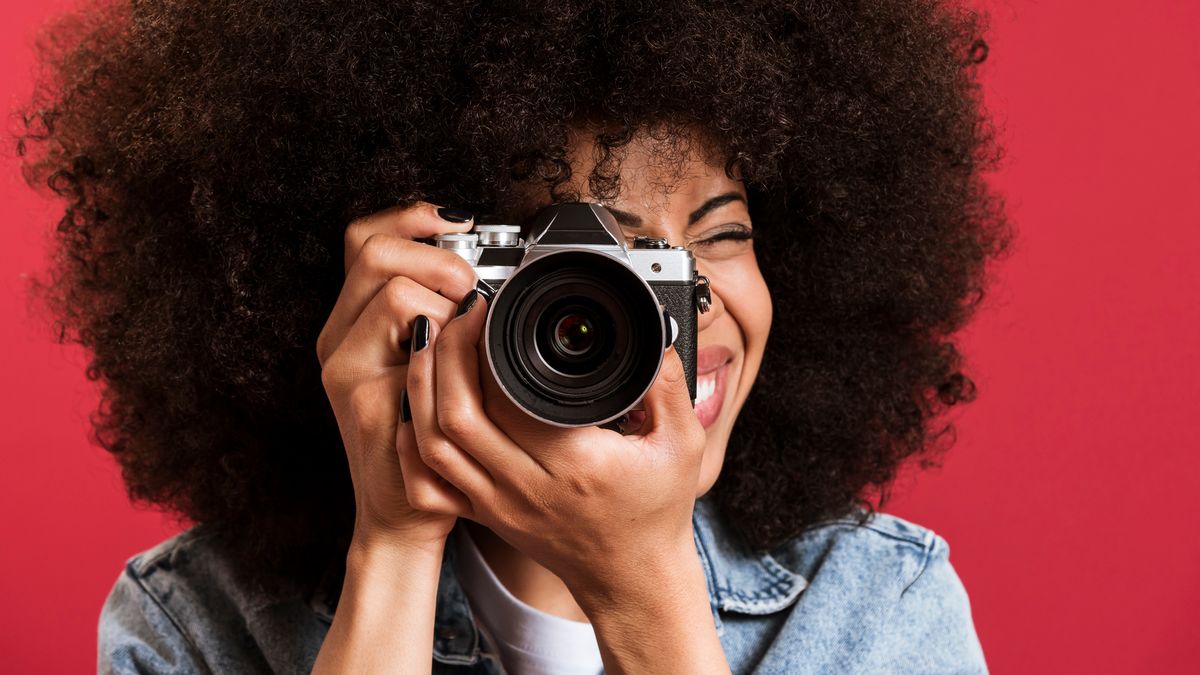 Black woman taking photo on vintage camera