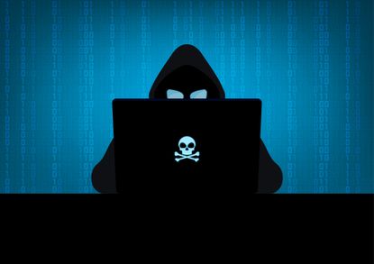 Silhouette of hacker wearing hood using laptop computer with glow in the dark blue skull and crossbones logo in dark room on blue binary code number background