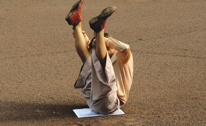 Boy sitting in middle of the road holding his legs