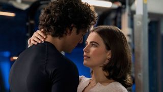A girl and boy lean into kiss in a changing room