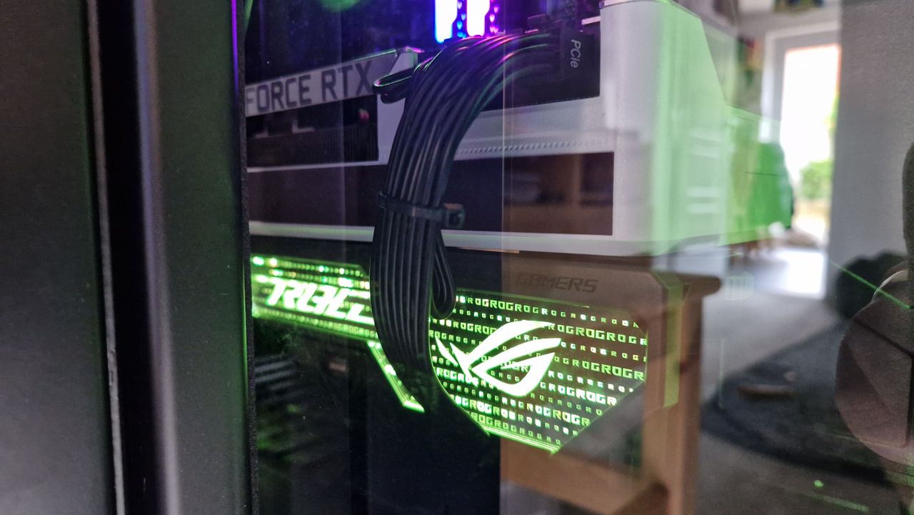 The Asus ROG Herculx GPU support bracket in a PC with its lights shining green.