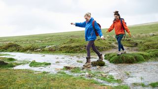 Two women in weatherproof clothing walking across a muddy hill