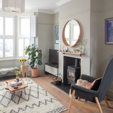 A grey-painted living room with a wood burning stove in the fireplace and a TV placed in a side alcove