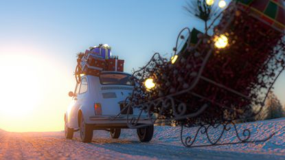 small old car with christmas trees on top pulling a sleigh