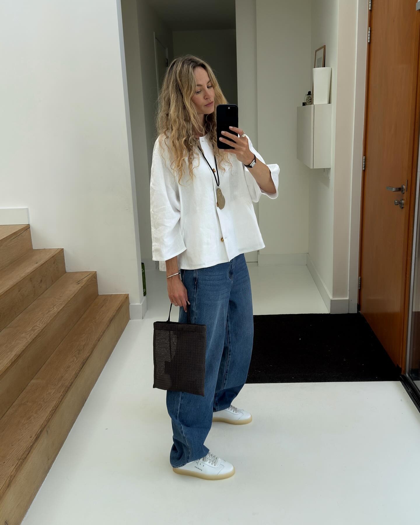 @anoukyve wearing Copenhagen Studios white sneakers, jeans, white button-down, mesh shopper bag, and pendant necklace