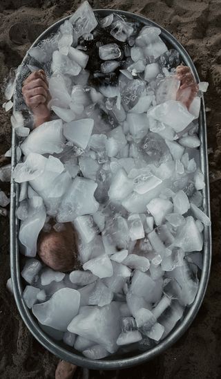 person in ice bath with knees and hands sticking out