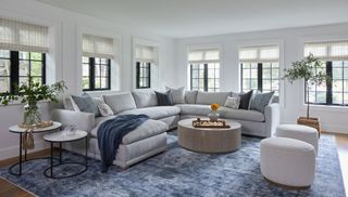 family room with gray rug and off white sectional sofa round footstools and steel framed windows