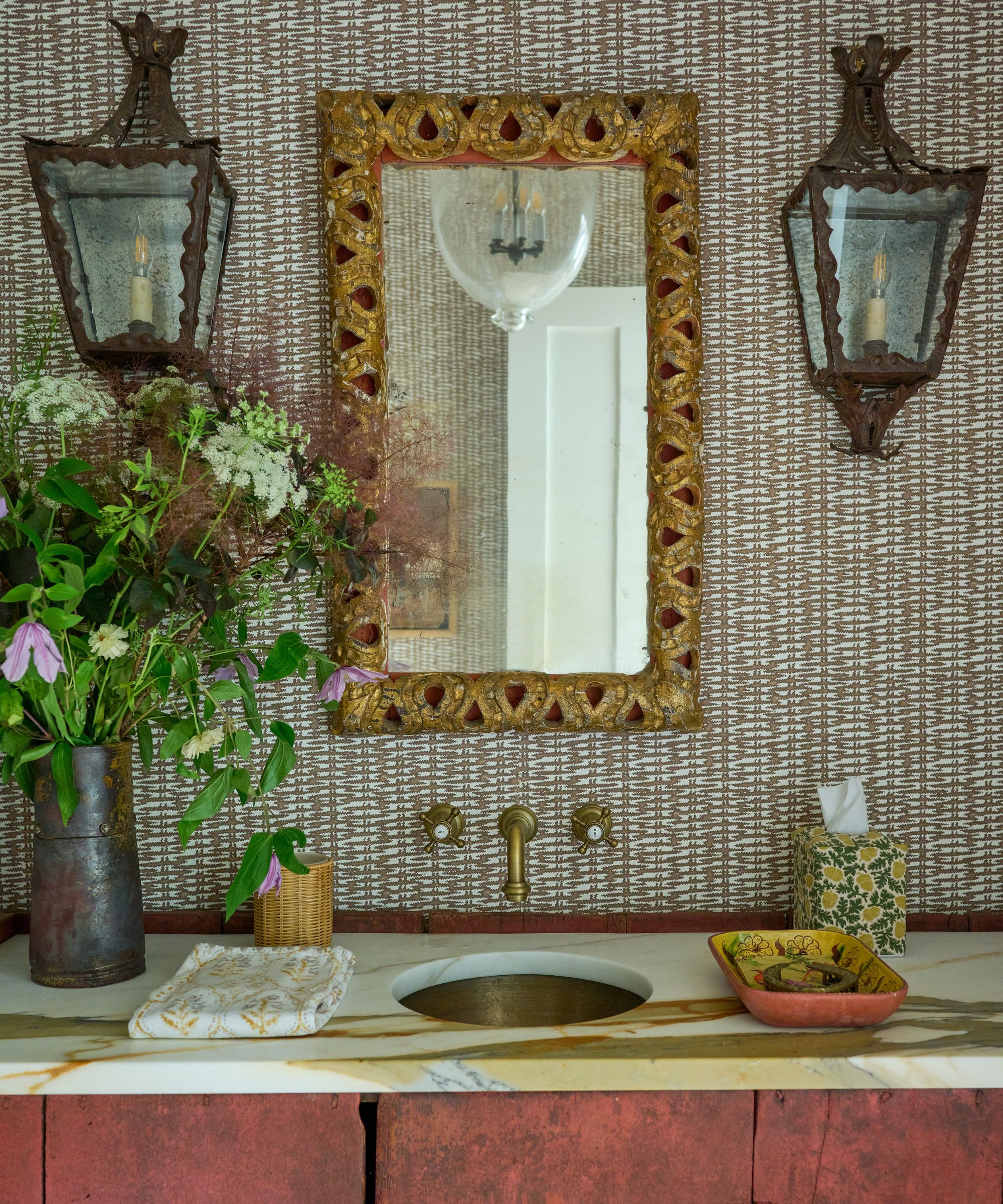 Bathroom vanity area with vintage lighting, gold vintage mirror and marble top