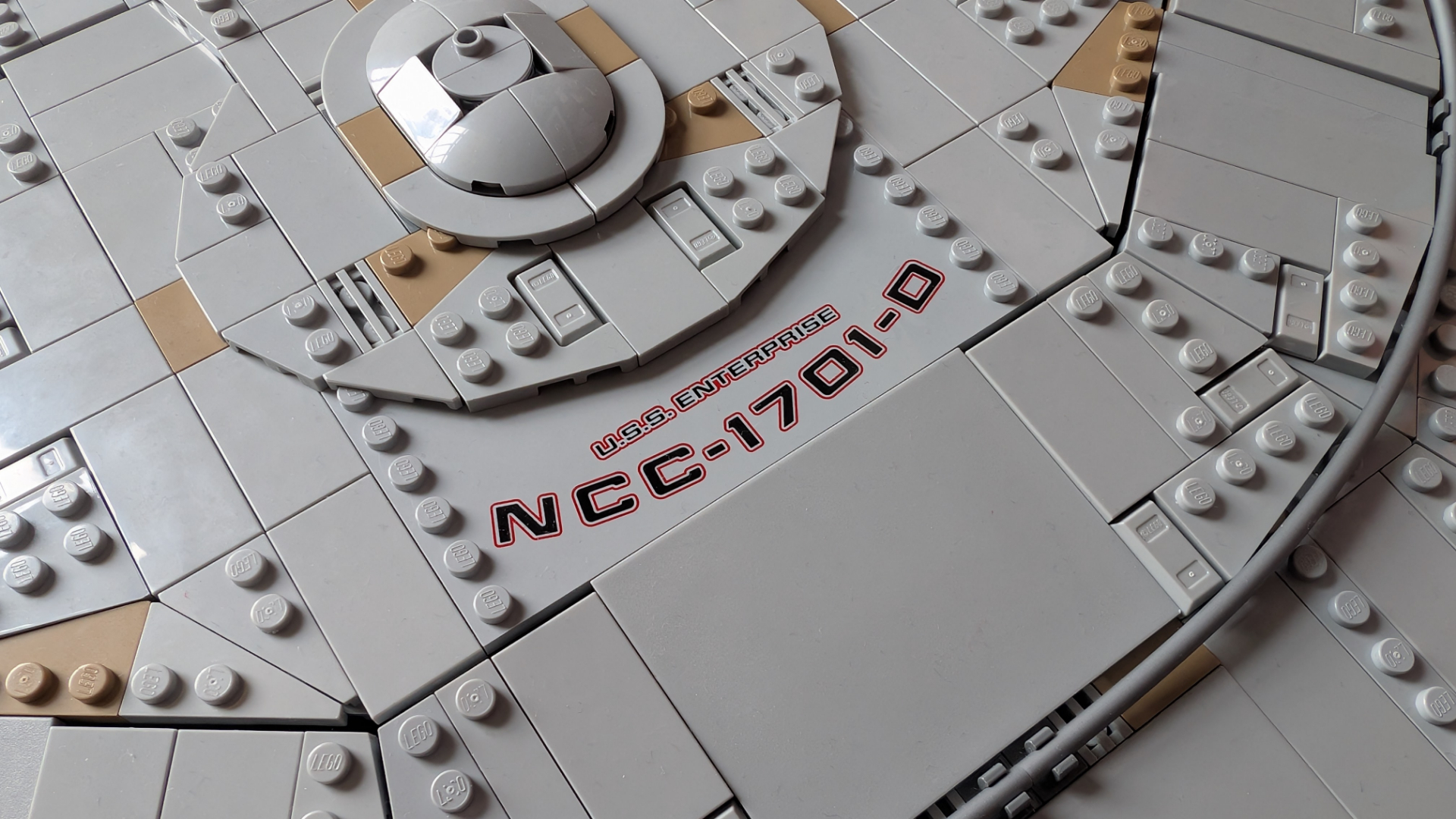Lego U.S.S. Enterprise set on stand, with a top-down view of the bridge and the ship's designation