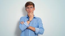 A young man holds his chin with a skeptical look on his face.