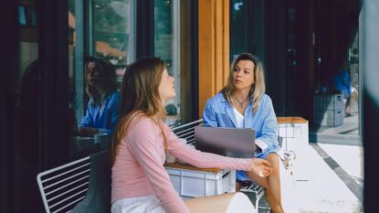A young woman works with her financial adviser on a terrace.