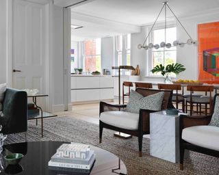 kitchen diner with white cabinets and white oval tulip table with wooden chairs, statement pendant and orange artwork