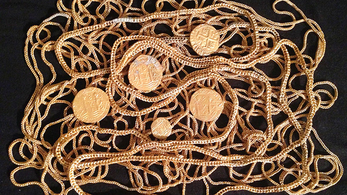 Gold coins and gold chains against a black background