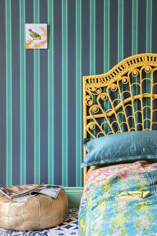 bedroom with striped wallpaper and tile inspired flooring and yellow bed frame as an example of how to mix pattern and prints in interiors by farrow and ball