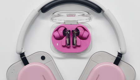Nothing Ear (3a) on a table with Nothing Headphone (a) below, both in pink to show the difference in colorways