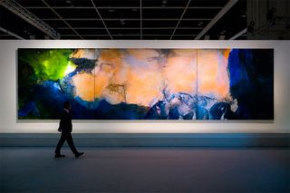 Man walking past and looking at large triptych painting