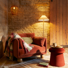 Dunelm mushroom footstool in a rusty red colour, next to a matching arm chair.