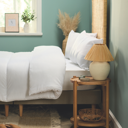 Double Aldi anti-allegergy duvet set and pillows on a double bed in a teal bedroom. There is a rattan headboard, woodan side table and rattan lamp.