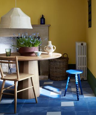 dining room with yellow walls and a blue floor and a round wooden table with lavender in the centre
