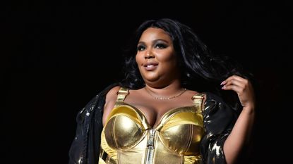 Lizzo performing on stage in a golden bodice