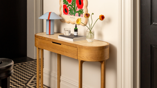 wooden console table in hallway with artwork and flowers