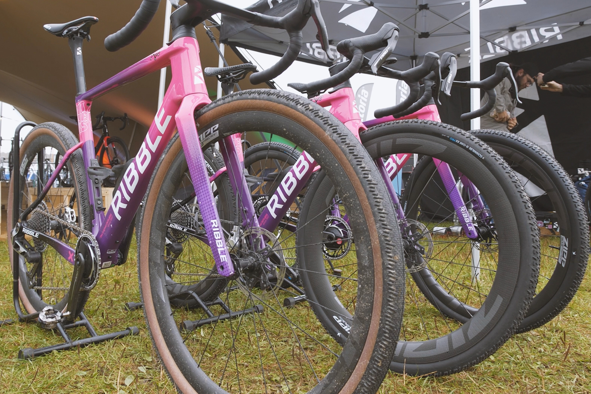 A pink and purple Ribble gravel bike being used by both male and female athletes on a misty day at British Gravel Champs